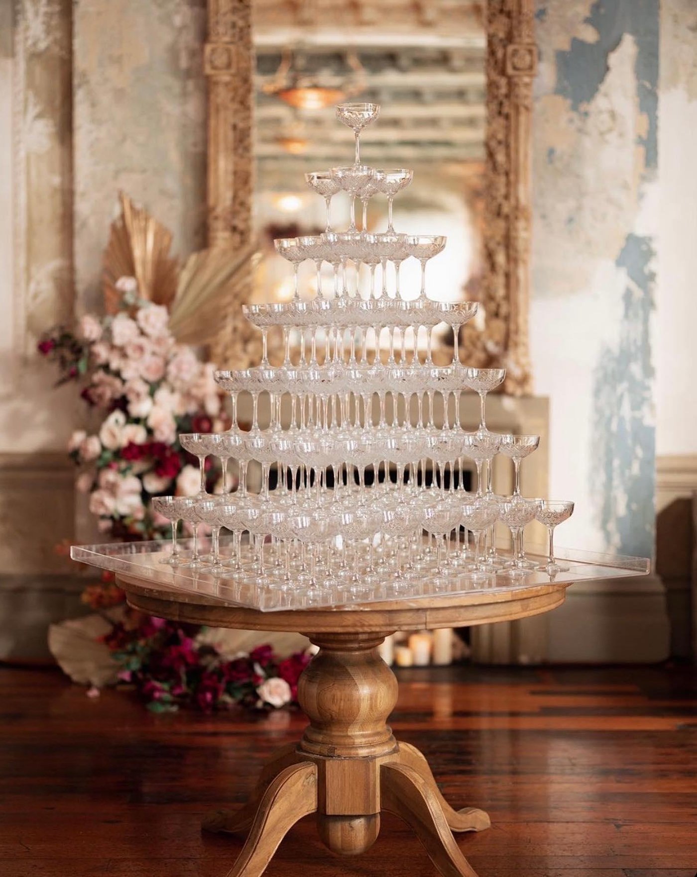 A tower of glasses on a wooden table in an elegant, vintage-style room.