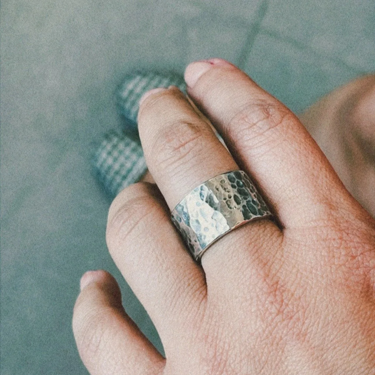 Mano con anillo de plata con diseño abstracto