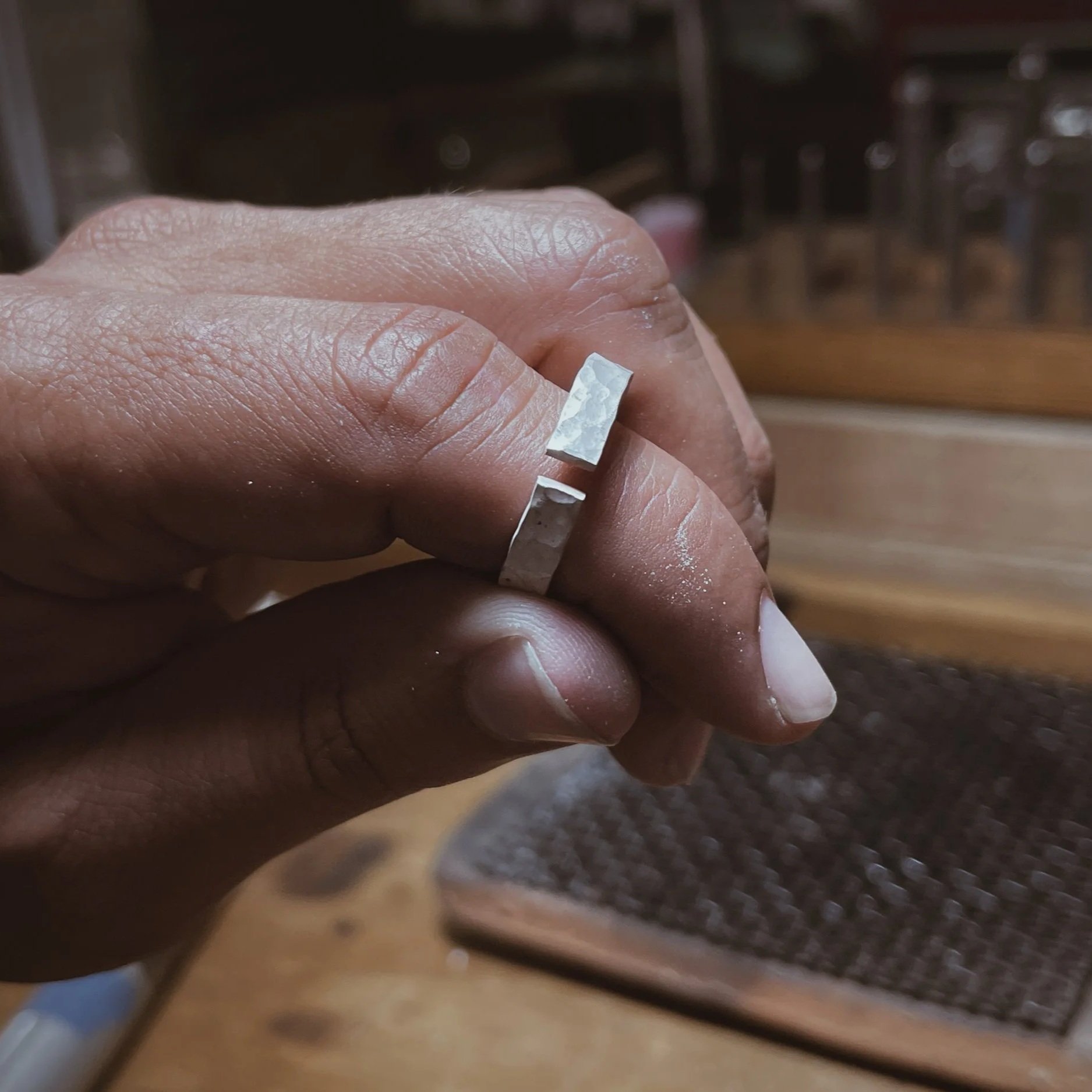 Mano sosteniendo anillo de plata en proceso