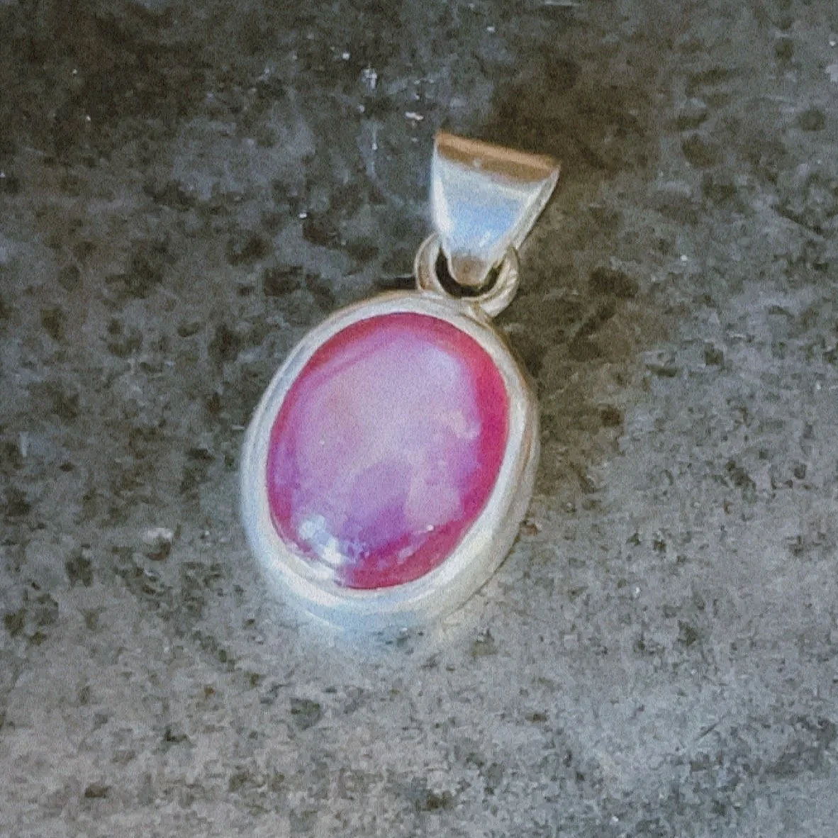 Dije de plata con una piedra roja en montaje tipo bisel.