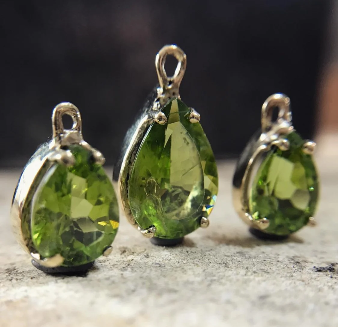 Aretes con piedras preciosas verdes, en forma de lágrima, en montaje de plata.