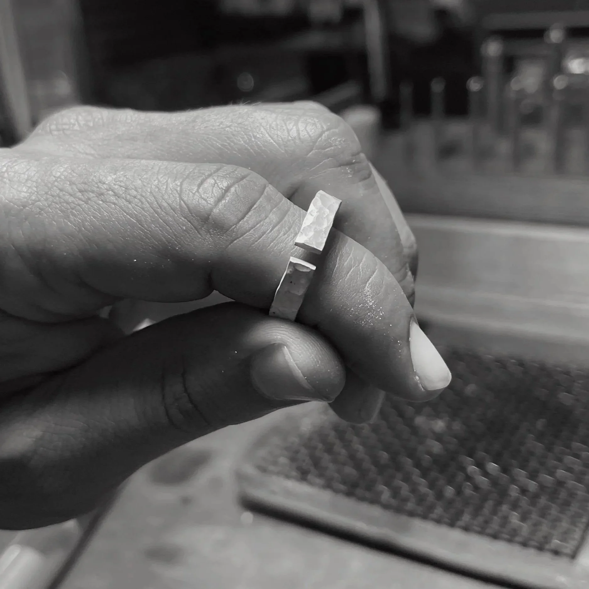 Mano sosteniendo un anillo de plata en proceso.