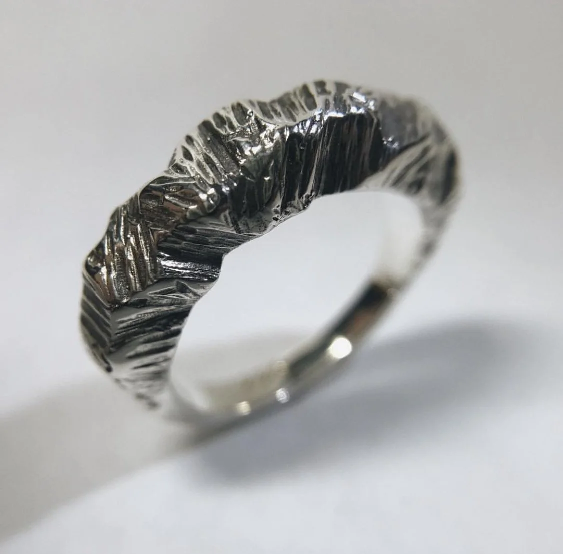 Anillo de plata con textura única y detalles en relieve.