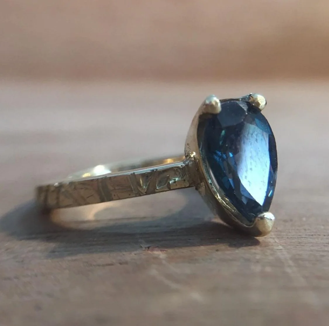 Anillo de plata con una piedra azul brillante en el centro.