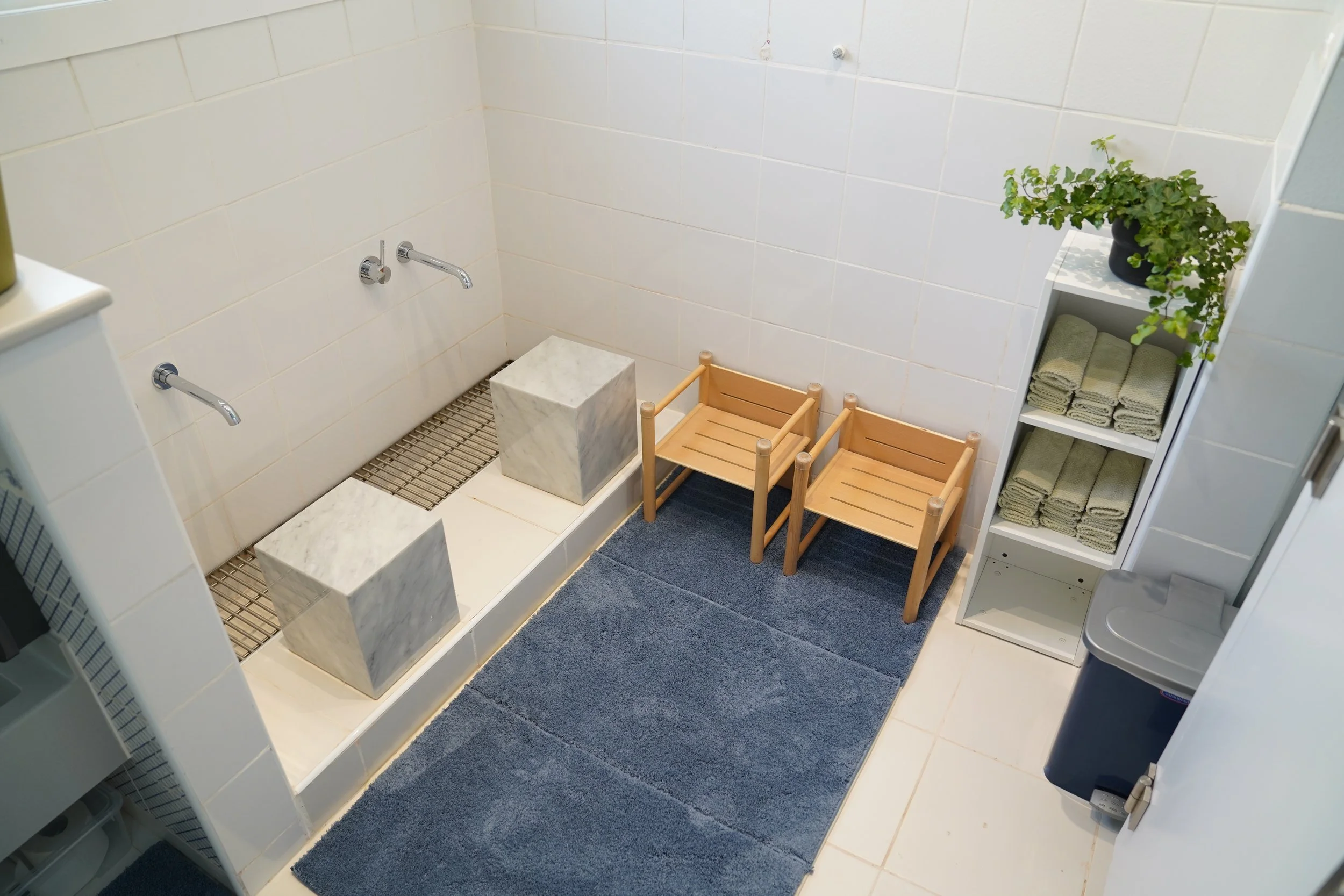 عمل فني بإطار زخرفي على حائط بجوار مدخل يؤدي إلى الحمام ذي البلاط البيج.