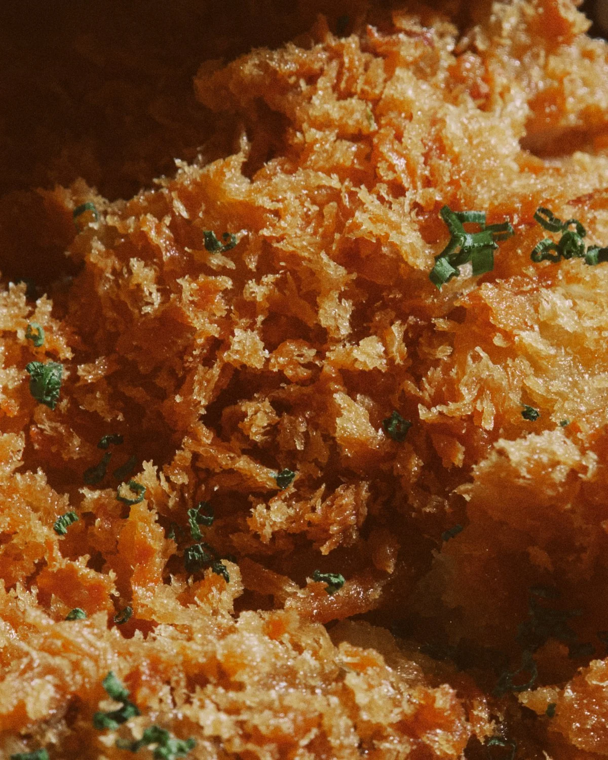 Close-up of crispy fried katsu garnished with chopped parsley.
