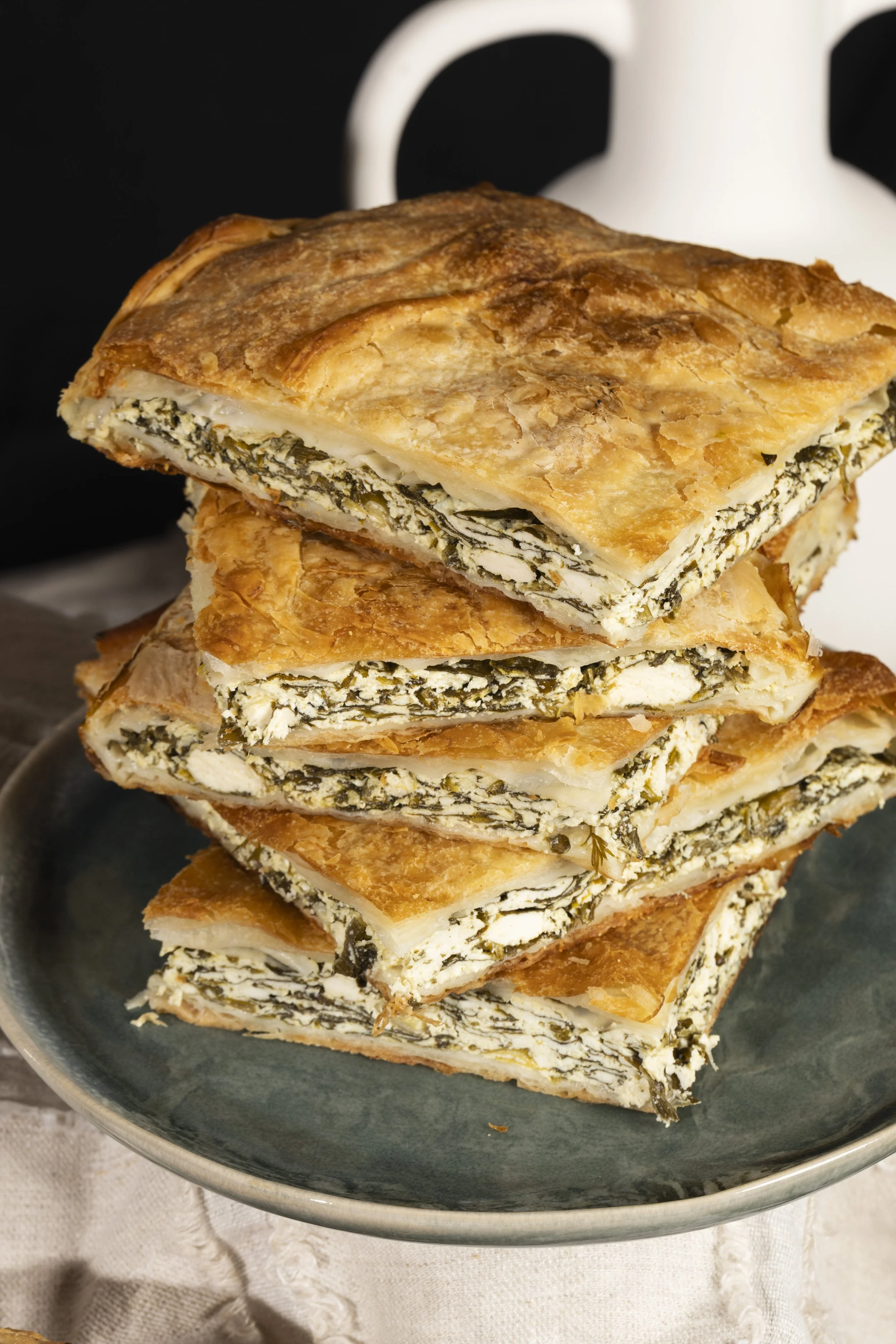 Stacked slices of spinach and cheese filo pastry on a dark plate