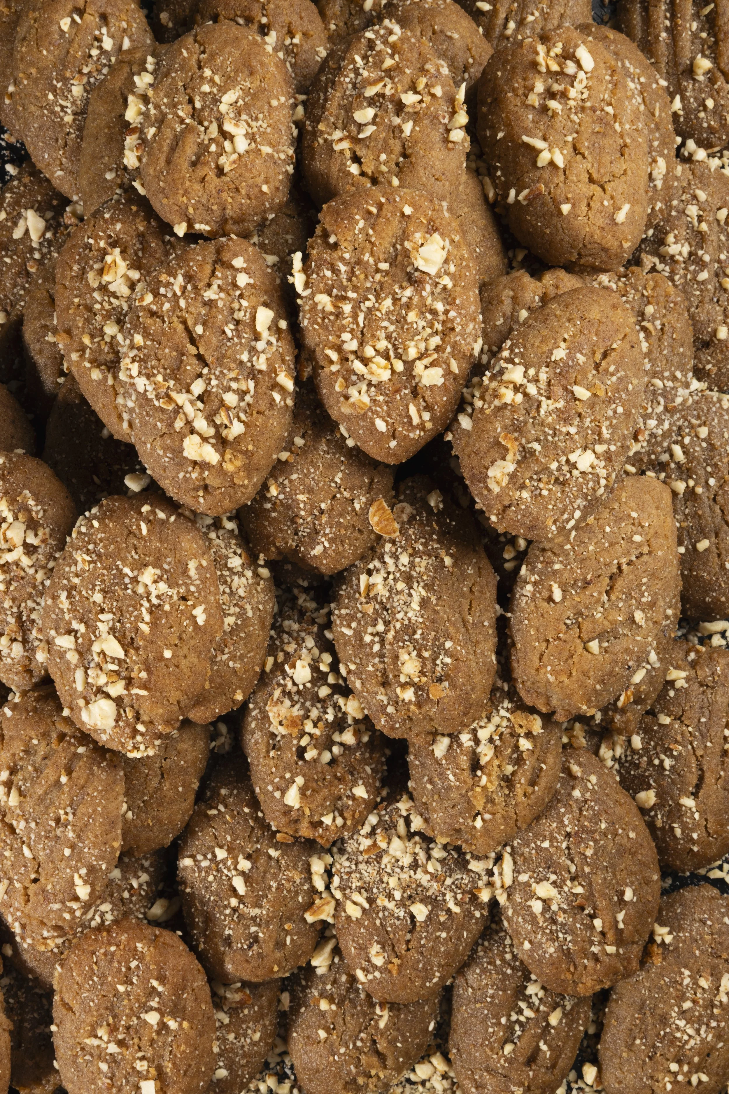 Close-up of multiple ginger cookies topped with chopped nuts.