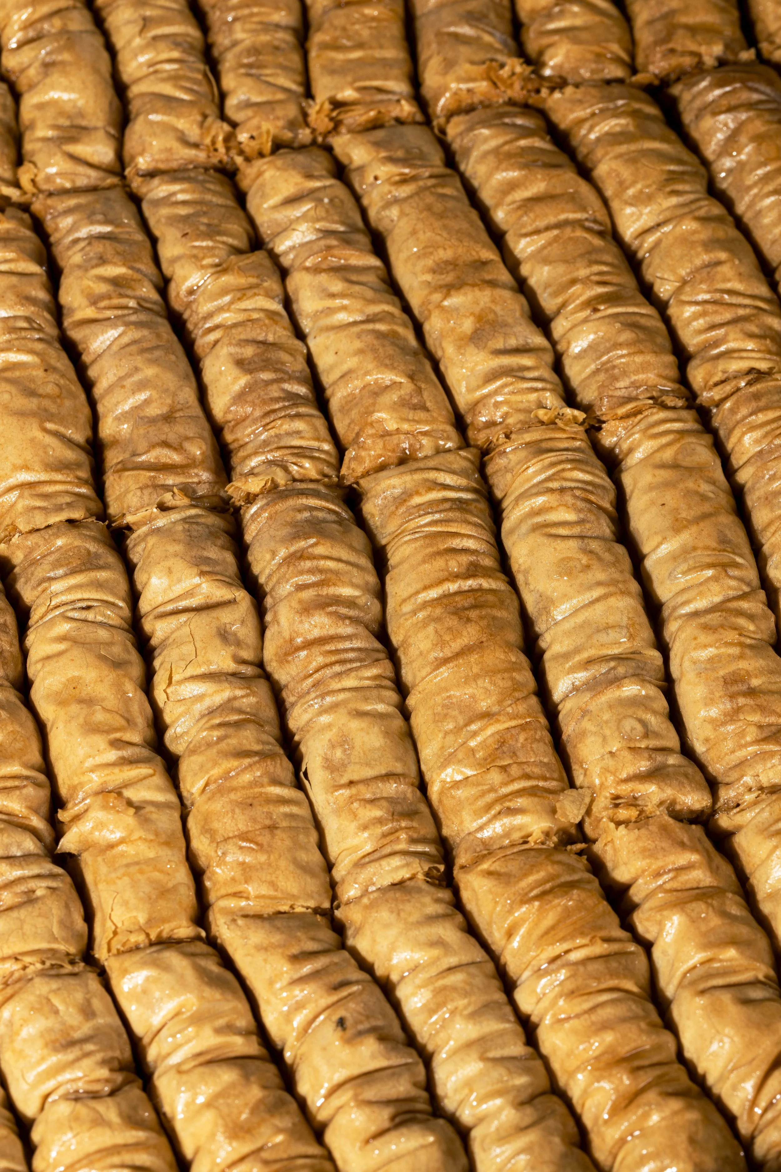 Close-up view of multiple grilled meat-filled pastry rolls arranged in a pattern.