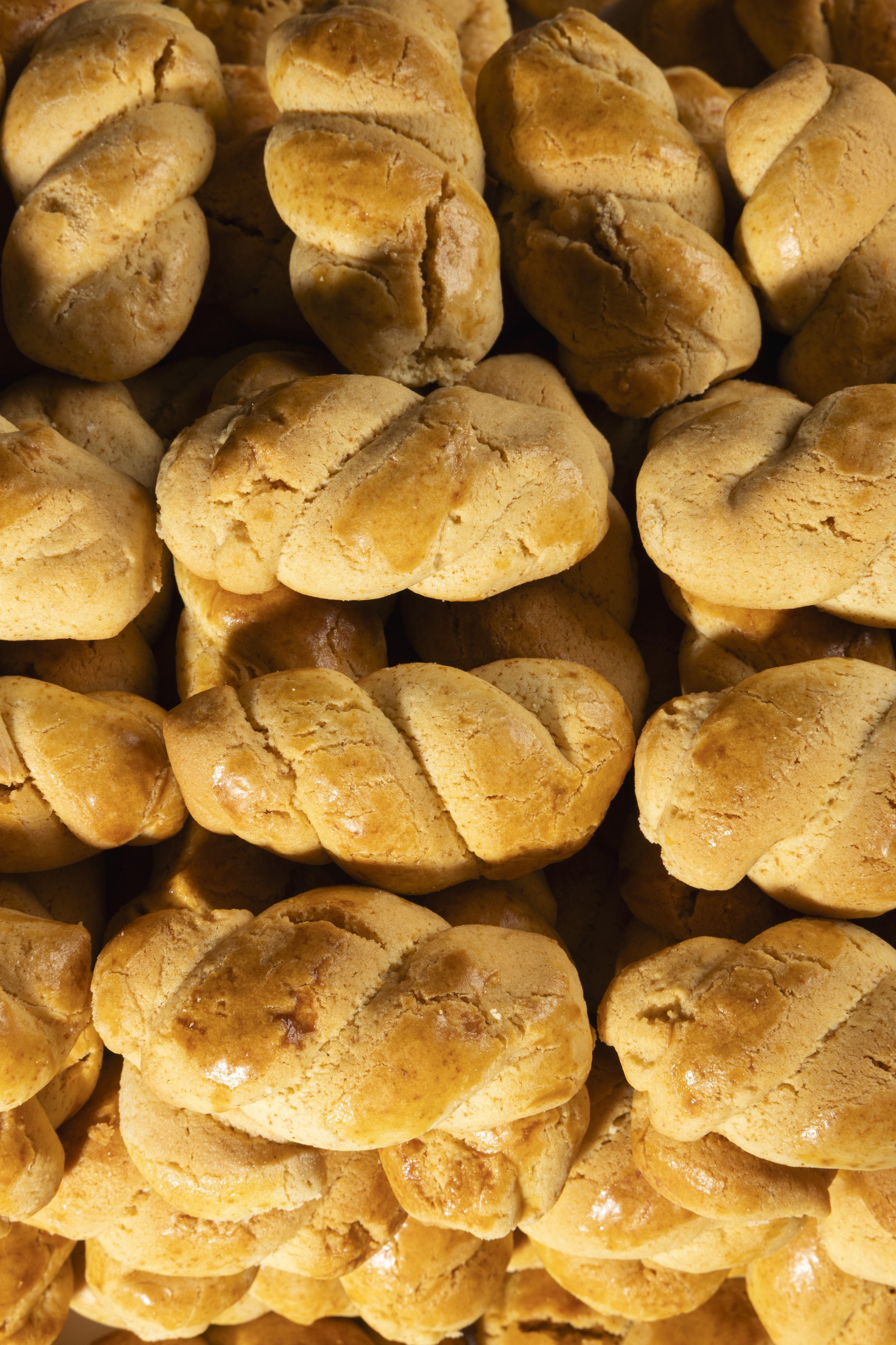 Close-up of a large pile of homemade cookies with a golden-brown crust.