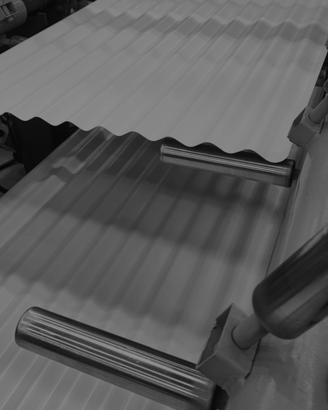 A metal rolling machine with corrugated metal sheets being processed.