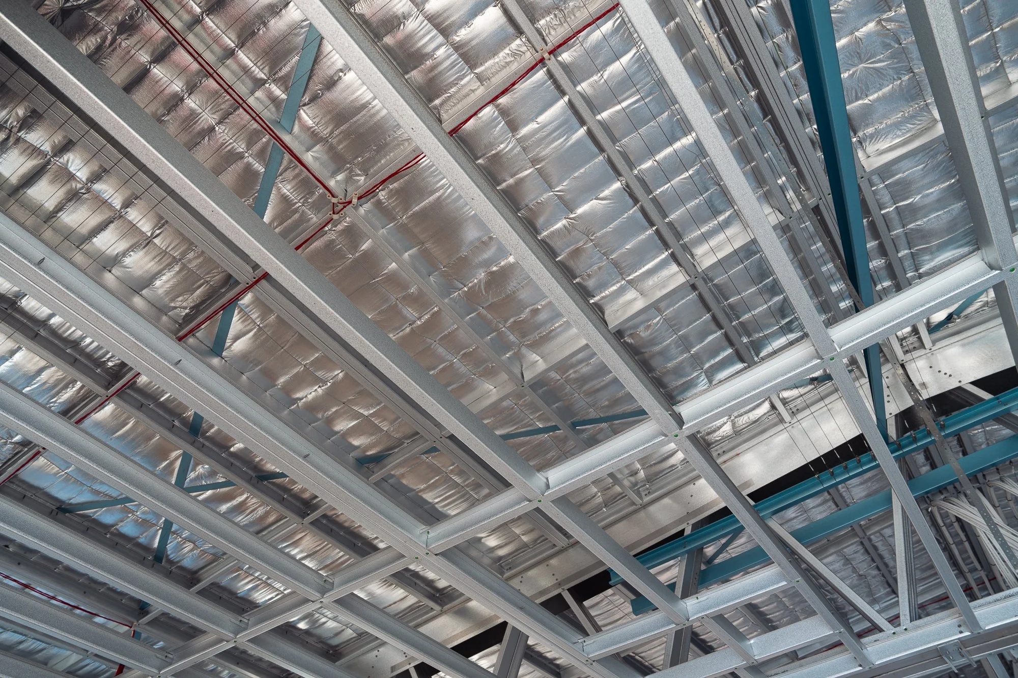 Construction site ceiling showing metal framework and insulation panels.