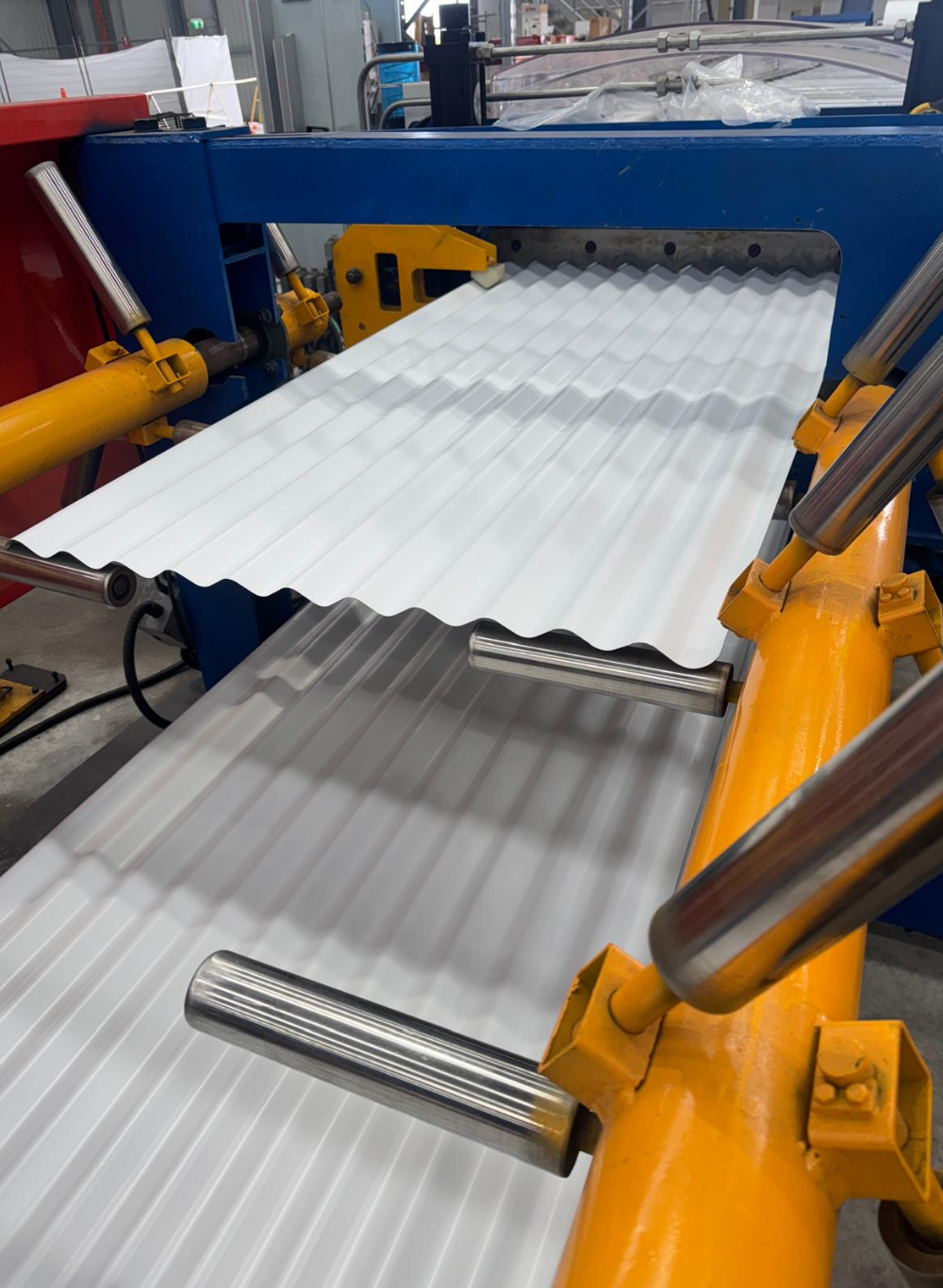 Industrial manufacturing process with corrugated metal sheets on a machine in a factory setting