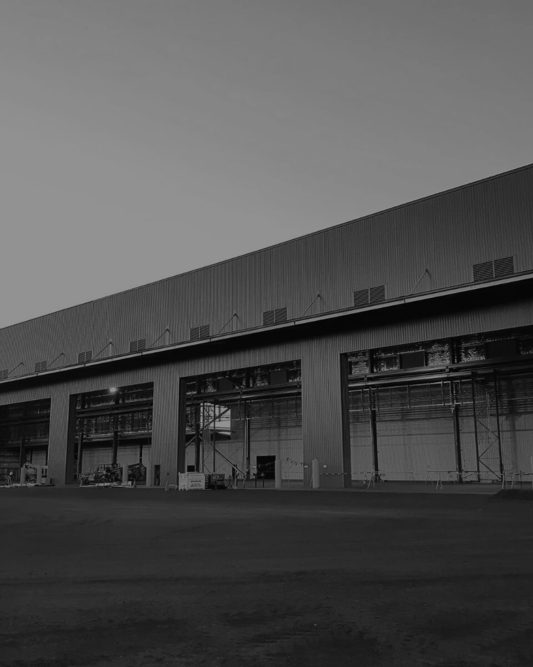 A large industrial building under construction with scaffolding and construction equipment outside.