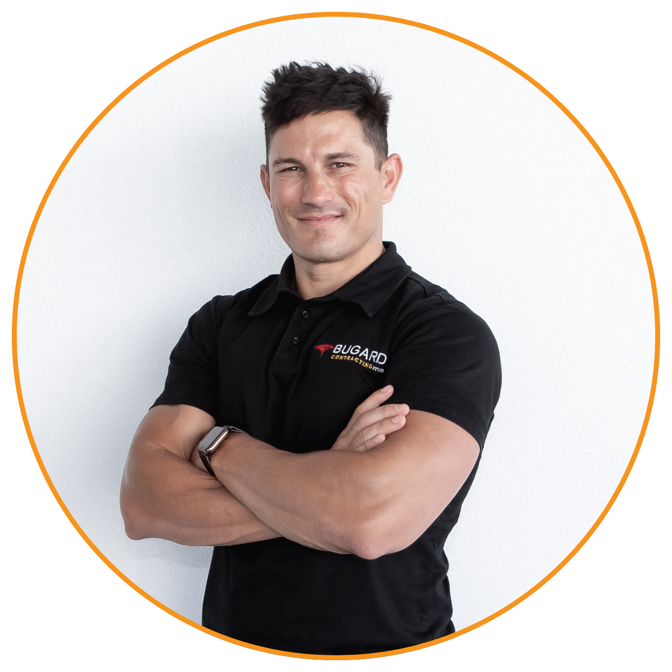 A young man with dark hair smiling and crossing his arms, wearing a black polo shirt with the logo 'BUGARD Contracting' on it, standing against a plain white background.