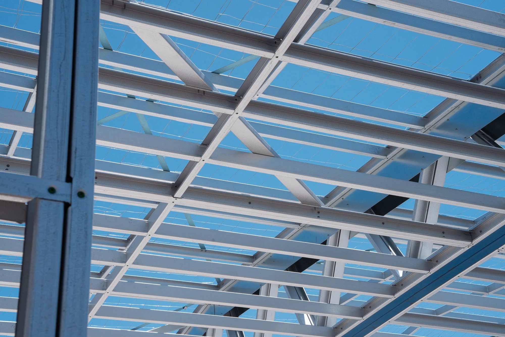 A low-angle view of a metal structure with solar panels, set against a clear blue sky.
