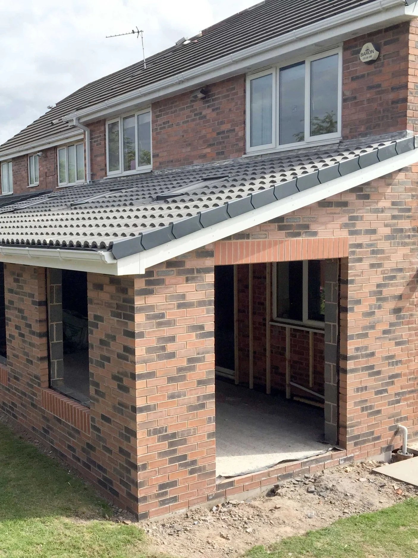 A two-story brick house under construction with an open garage and sliding windows on the second floor.