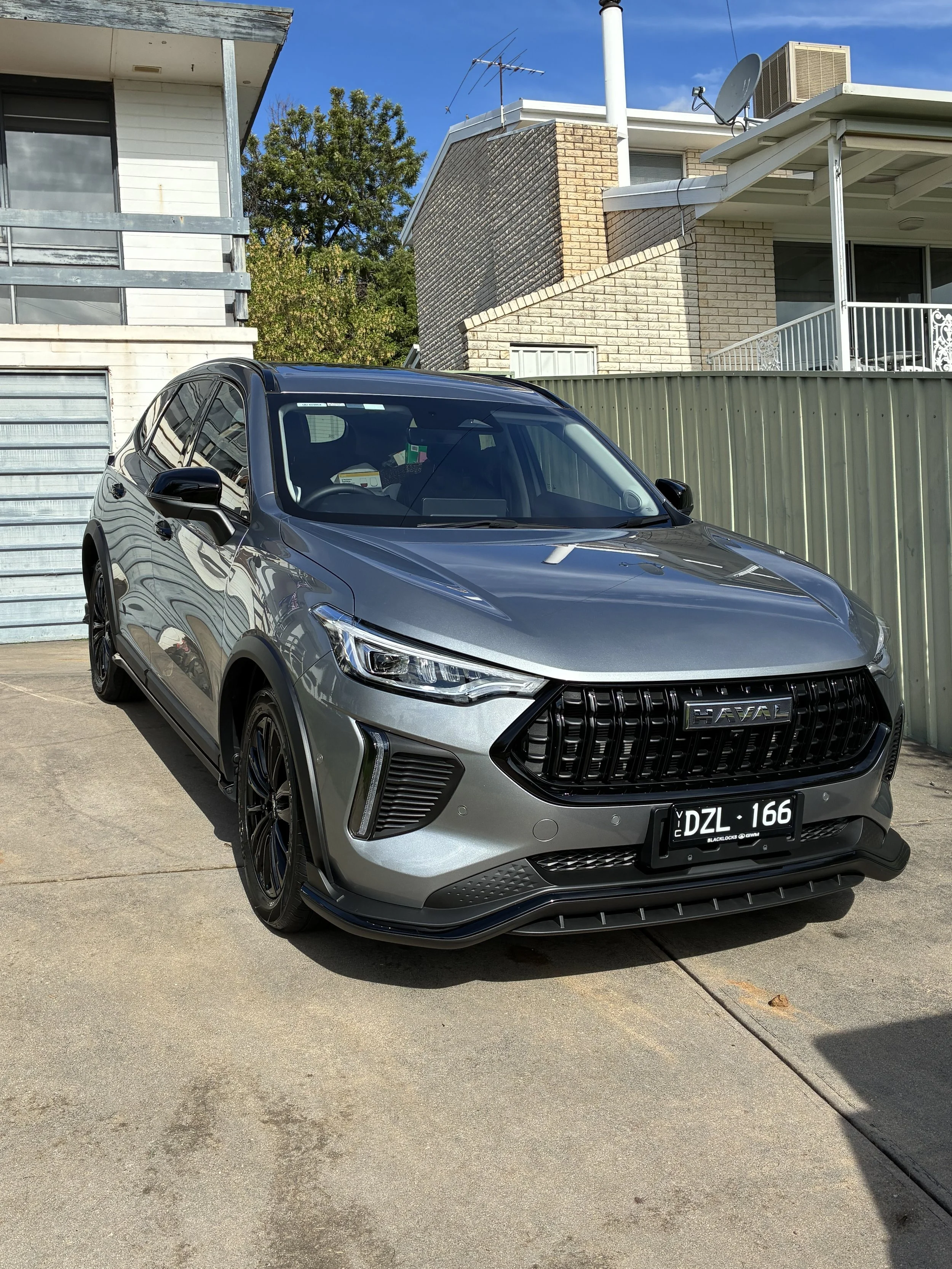 Silver Haval SUV parked in driveway of a residential area on a sunny day.