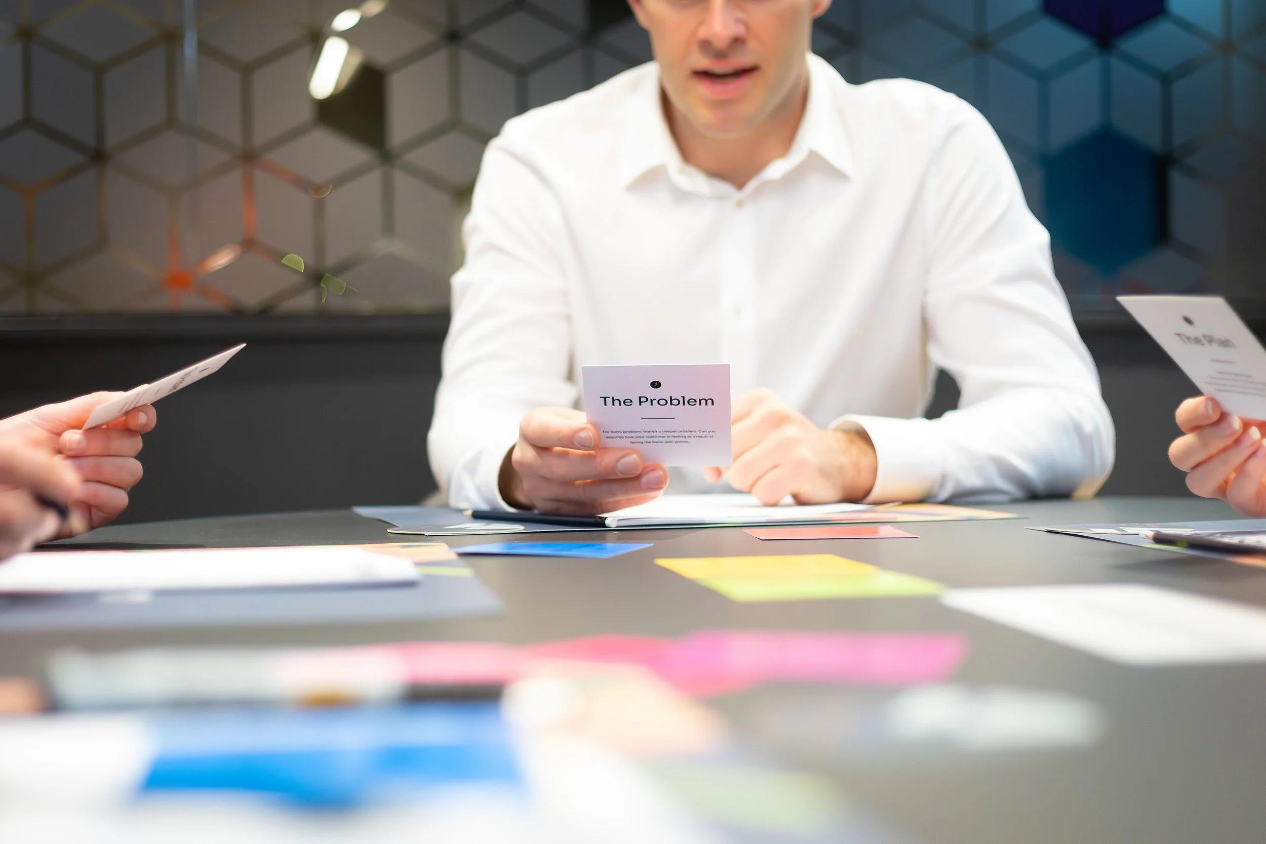 a group of people holding workshop prompt cards in a value proposition workshop, hosted in a modern office environment