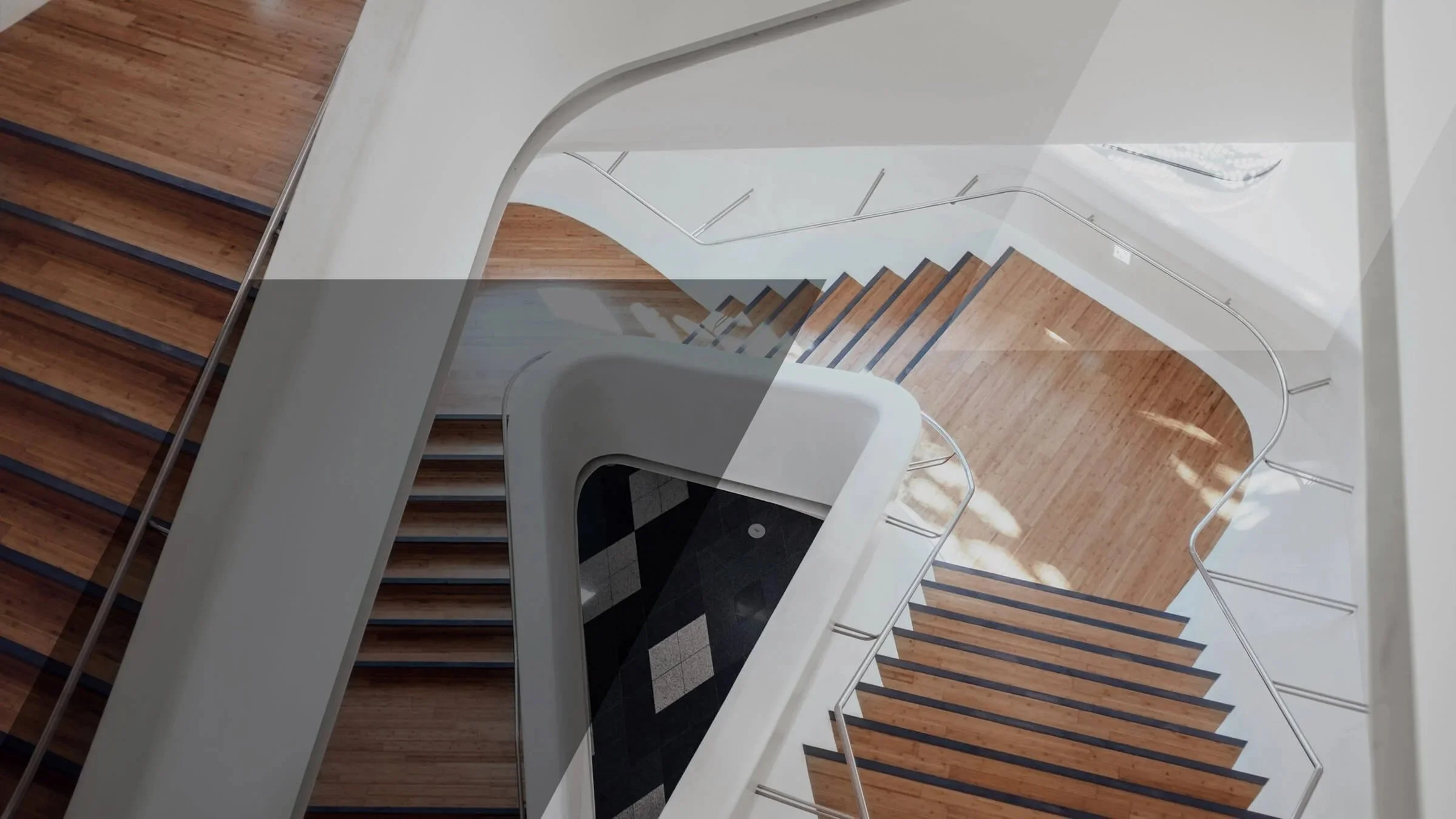 Aufsicht auf eine moderne Treppe mit Holzboden und weißen Wänden, Blick nach unten auf den Betrachter.