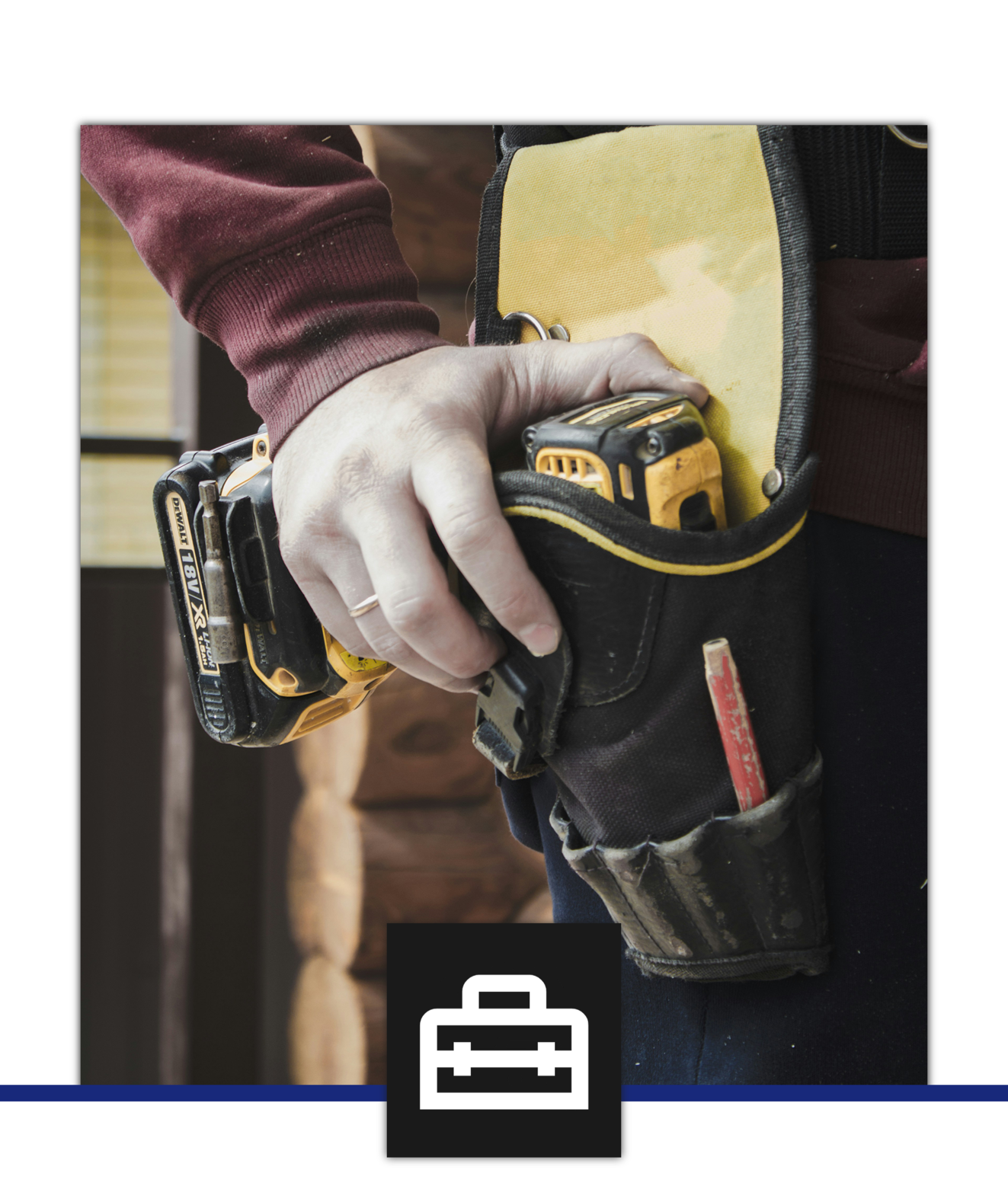 Hand hält einen schwarzen und gelben Akkuschrauber, trägt eine Arbeitshose mit Werkzeugtasche mit Schraubenzieher, vor einem Holzhaus.