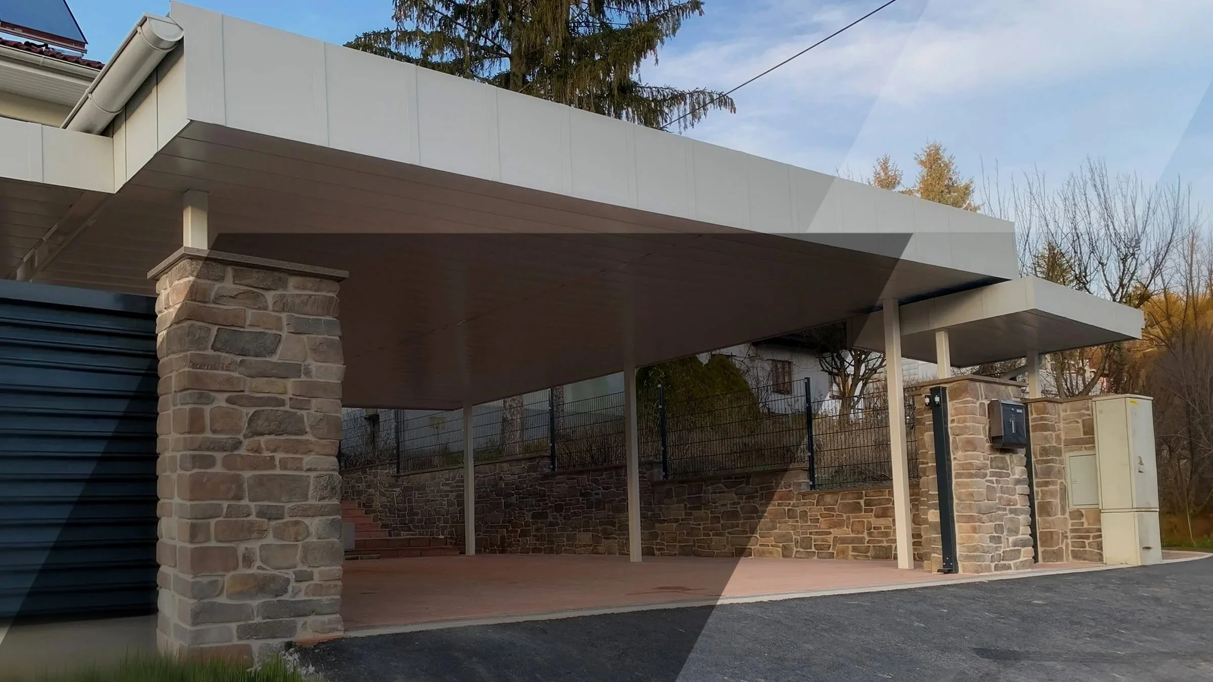 Maßgefertigter Carport von MTP mit weißen Metalldach und stabilen Steinpfeilern, funktional und stilvoll für Ihr Zuhause. Maßgefertigte Metallkonstruktion aus Stahl und Aluminium von MTP in Kottingbrunn