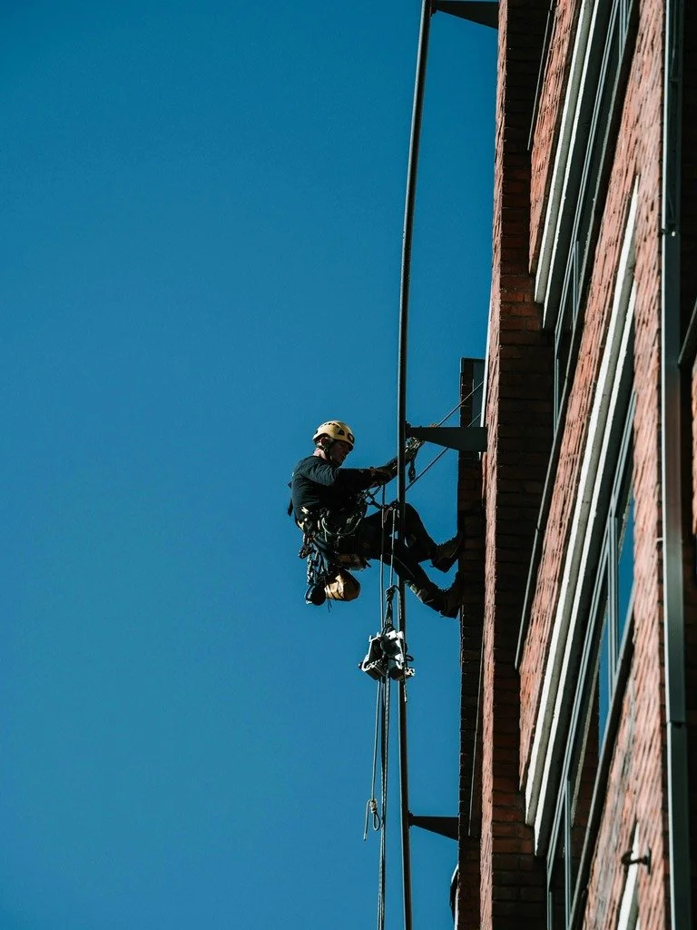 Mann mit Sicherheistausrüstung auf einer Haus Wand