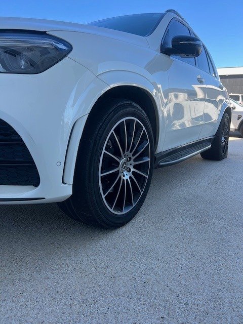White SUV parked on a concrete surface under a clear blue sky.
