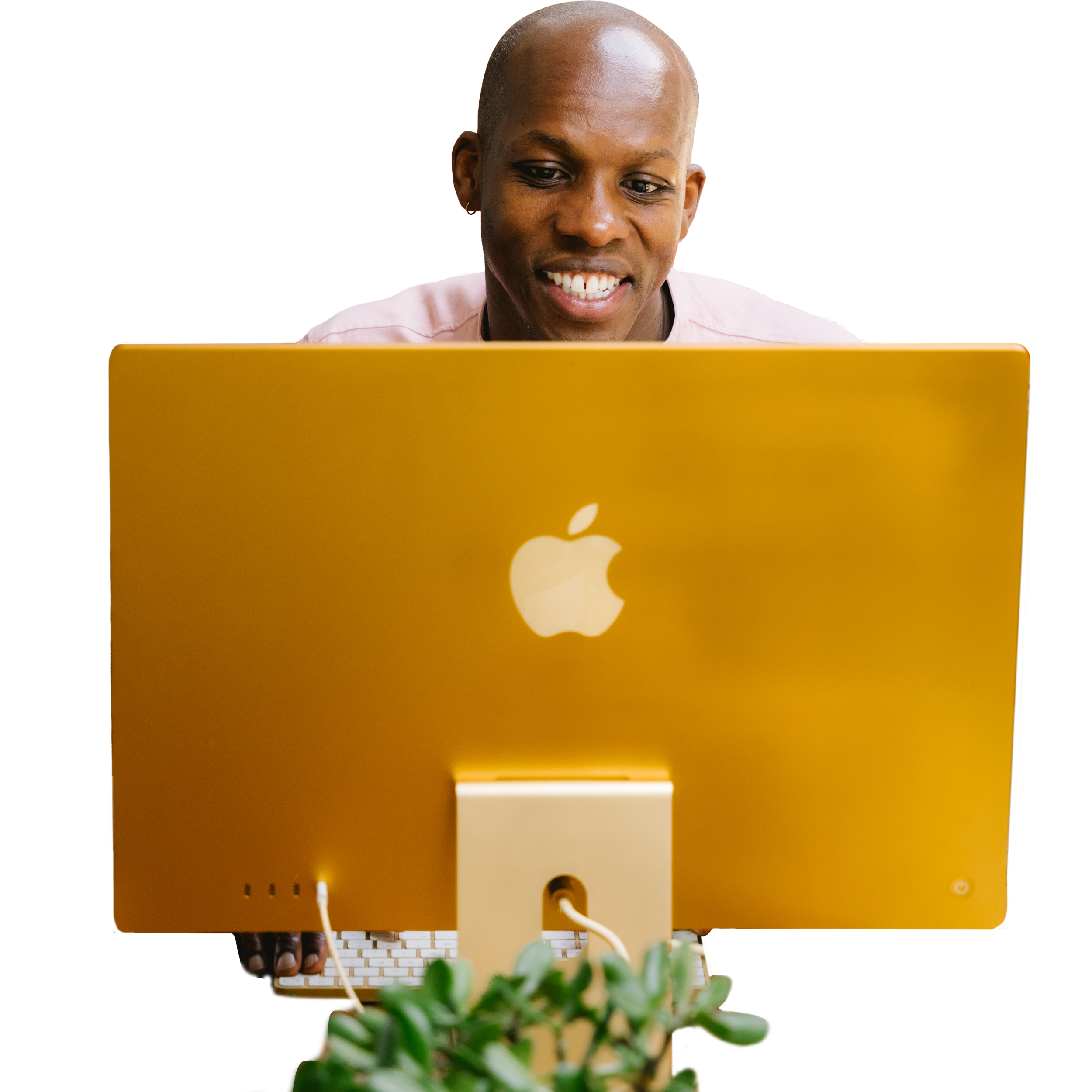 A man is looking at a yellow Apple desktop computer with a white Apple logo on the back, smiling.