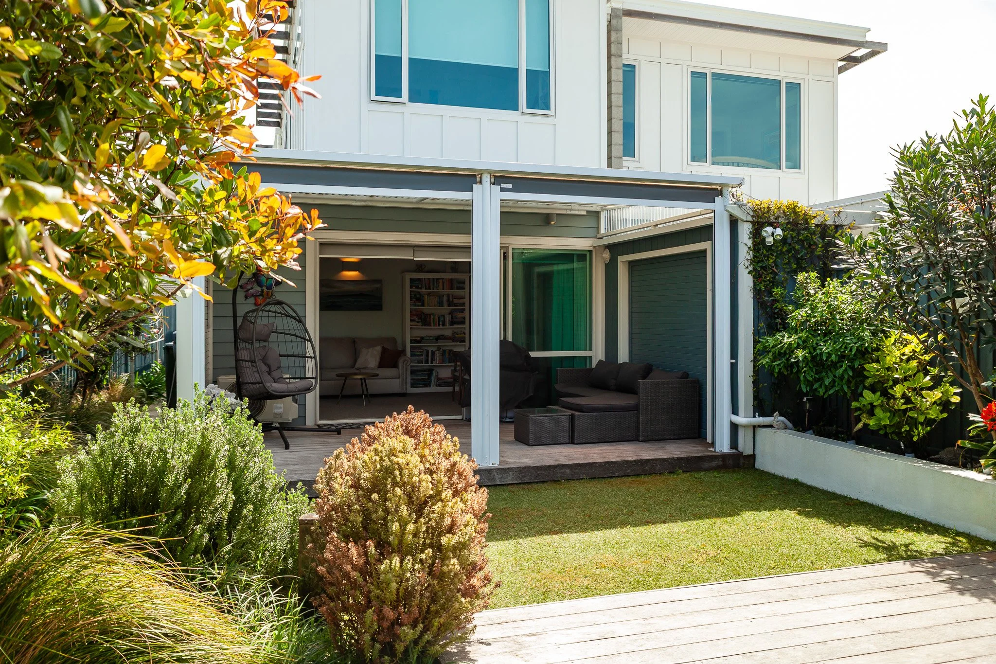 Backyard patio with outdoor seating, plants, and house with large windows