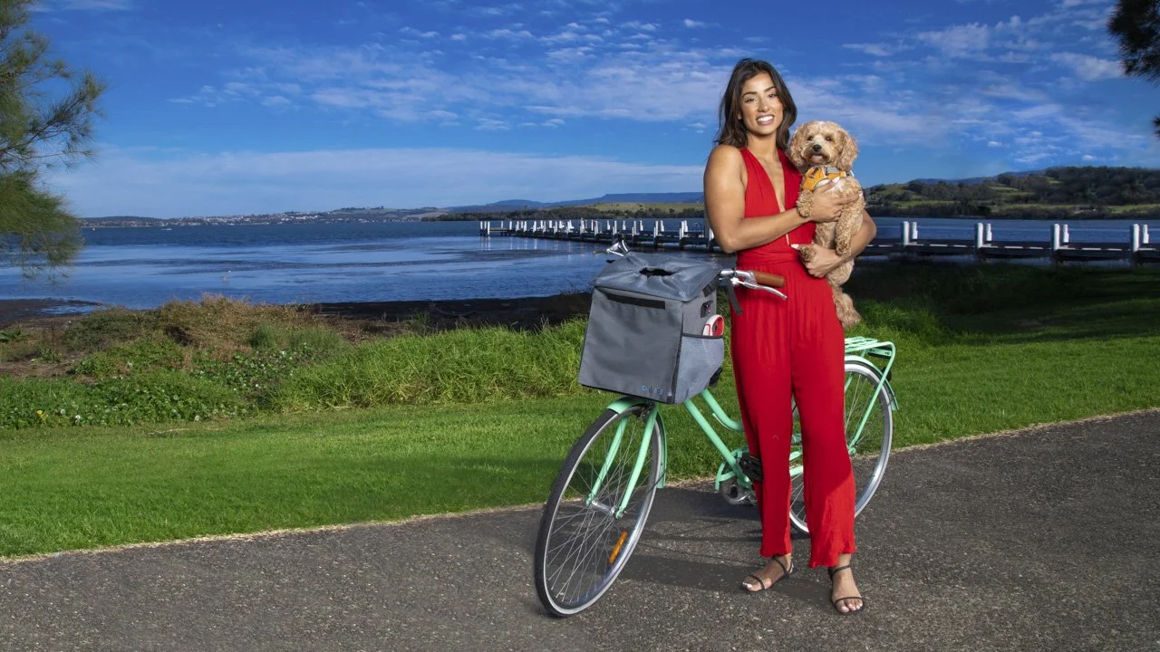 Woman walking outdoors with Chillbug pet carrier backpack and small dog, wearing activewear at sunset near lake – lifestyle product photo captured by Cole Studios.
