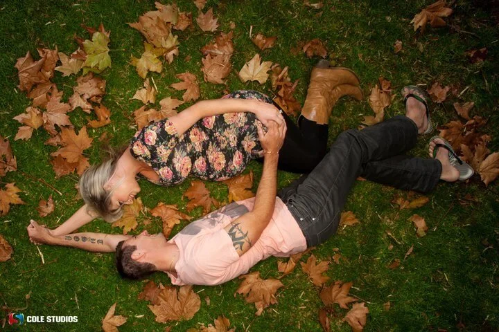 Couple lying together among autumn leaves
