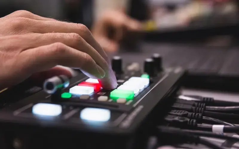 Close-up of a hand adjusting music production equipment with colorful buttons and knobs.