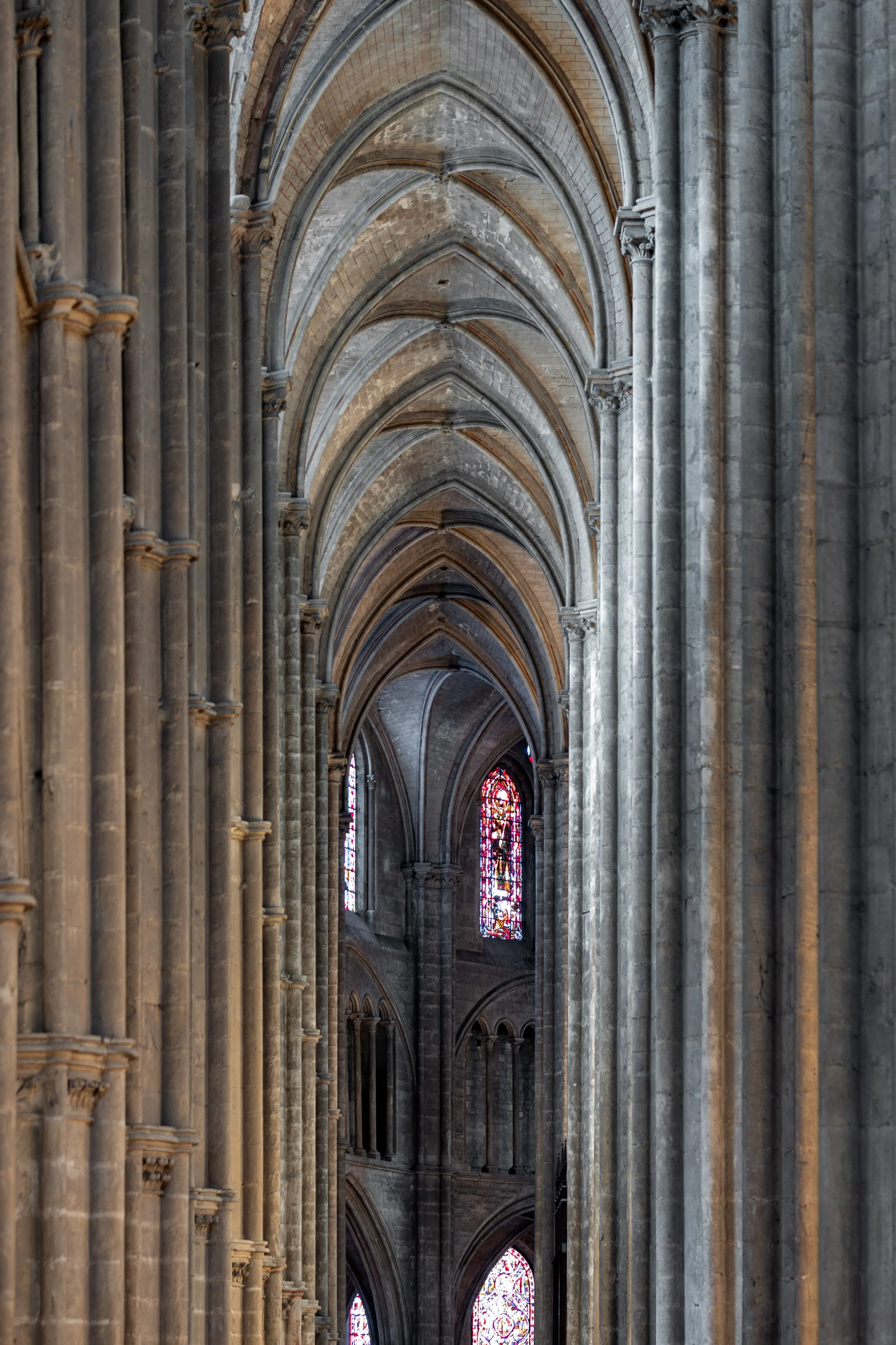 Interior view of a Gothic cathedral with pointed arches, stone columns, and stained glass windows.