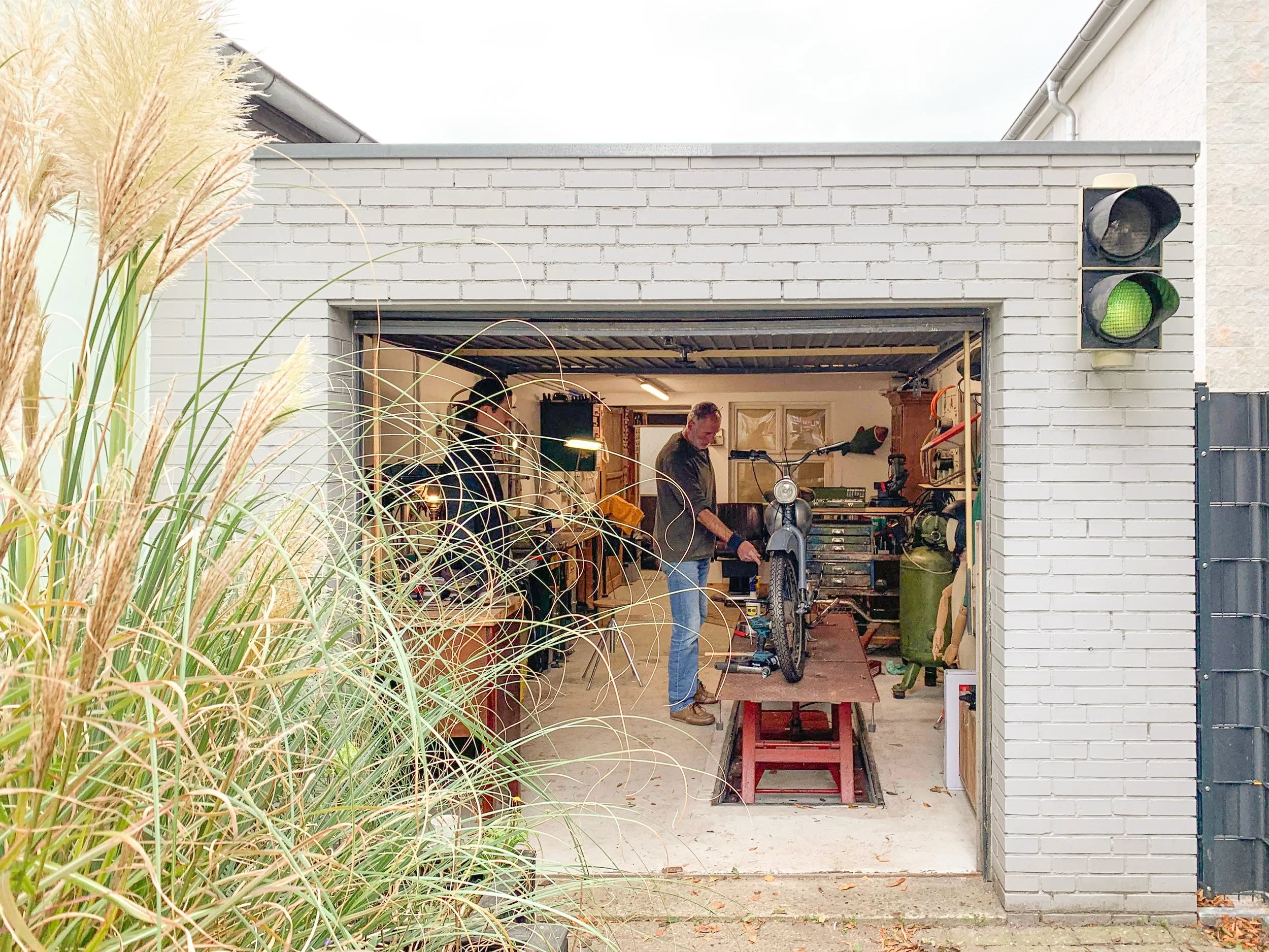 Einblick in eine Garage, die als Motorrad-Werkstatt genutzt wird, mit Hebebühne und Werkbank.
