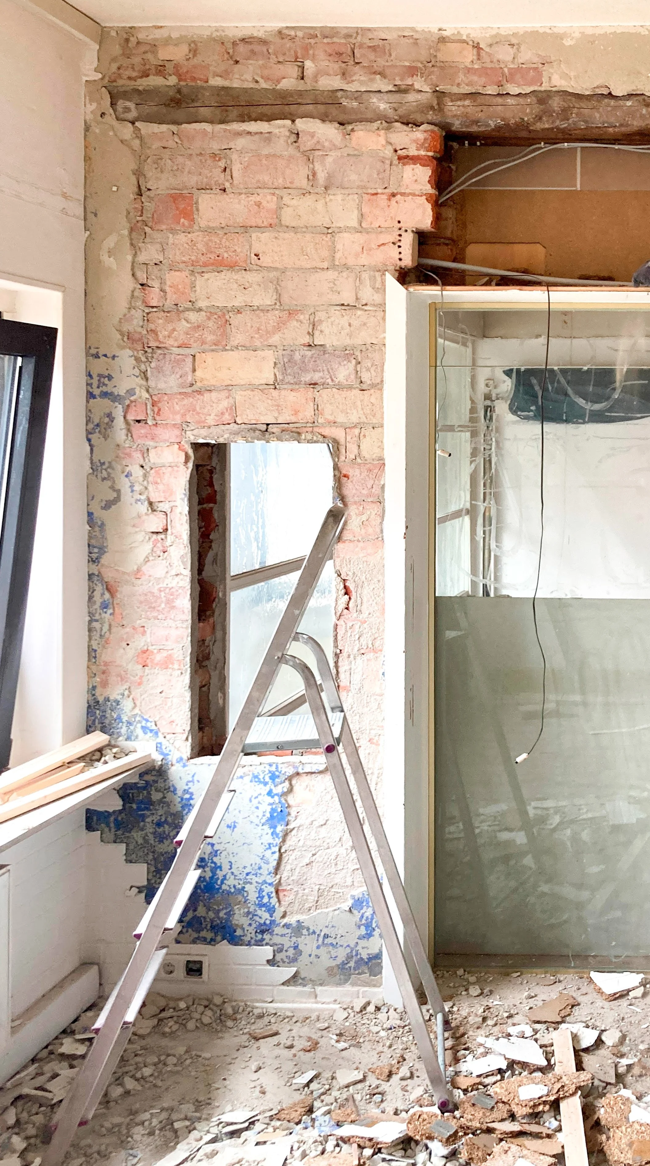 Baustelle Kernsanierung: Freigelegtes Ziegelmauerwerk mit altem Holzsturz und Bauschutt.