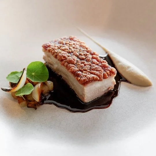 A plated dessert with a piece of fried fish, sauce, and garnishes.