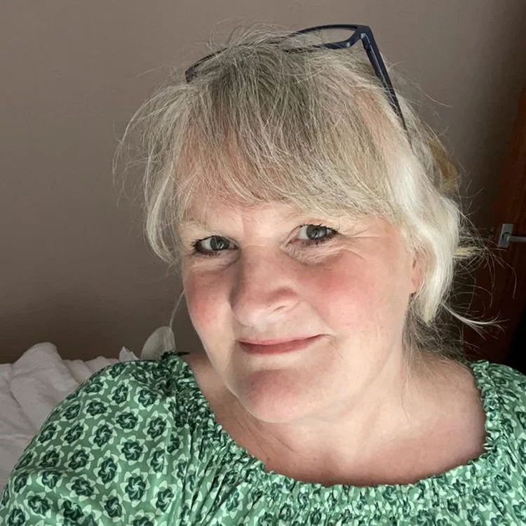 Headshot portrait of a lady wearing a green top smiling at the camera