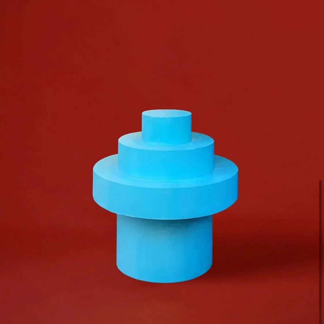 A light blue, tiered, abstract sculpture set against a red background.