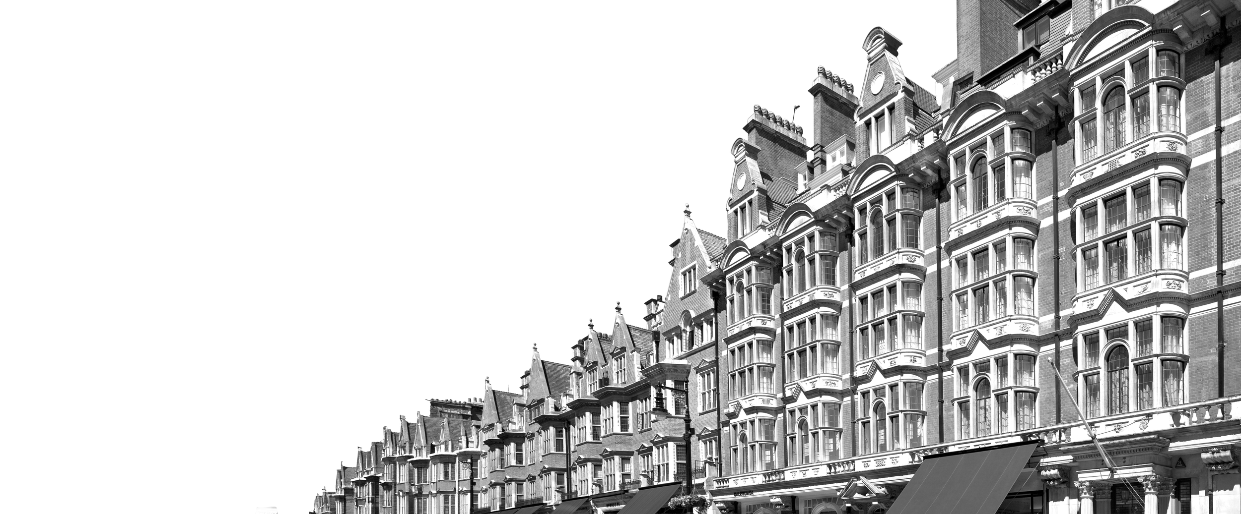 Black and white photo of historic multi-story brick buildings with intricate architectural details, bay windows, and decorative parapets.