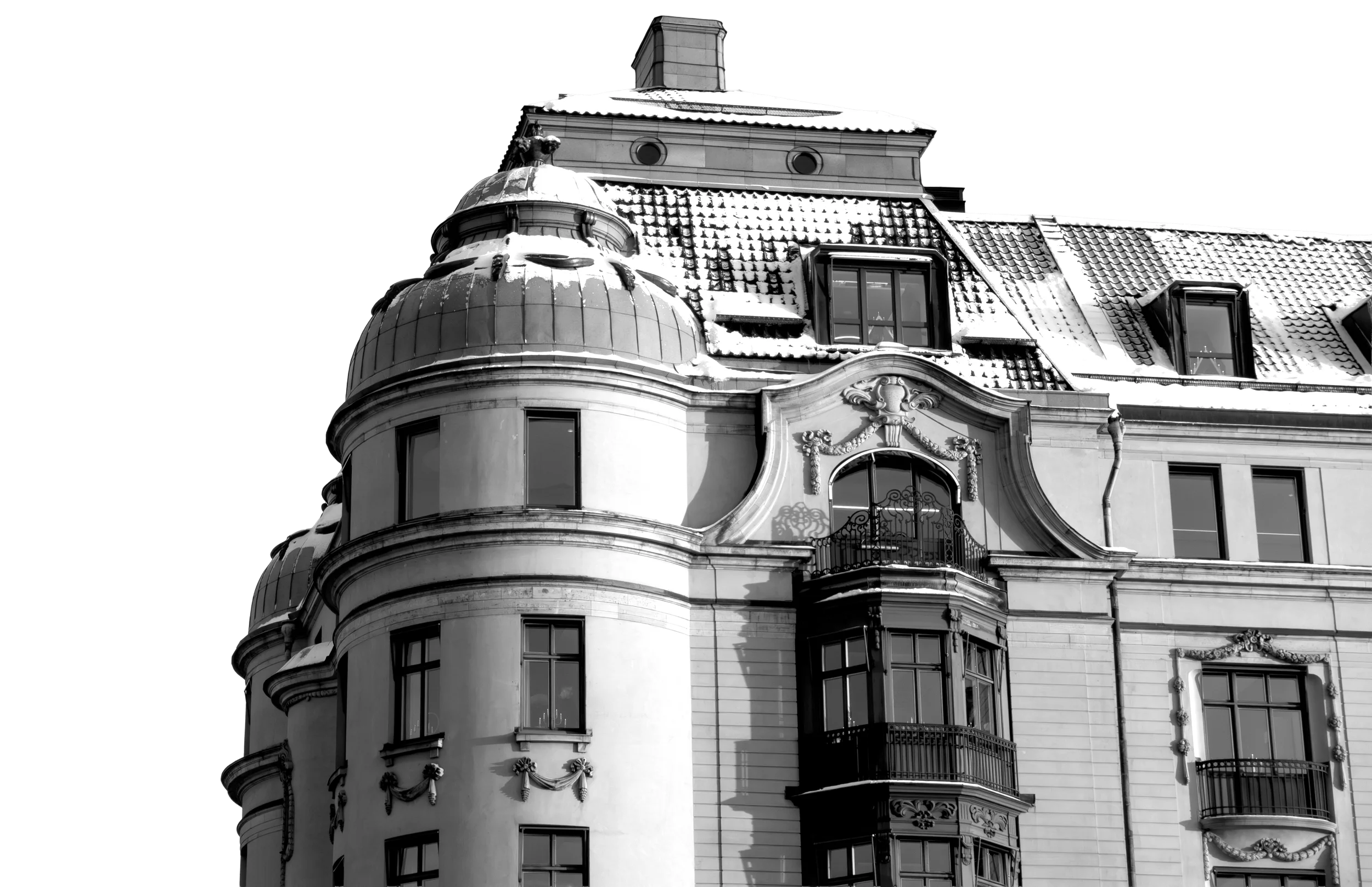 Black and white photo of a historic building with ornate architectural details, multiple windows, a rounded turret, and a snow-covered roof.