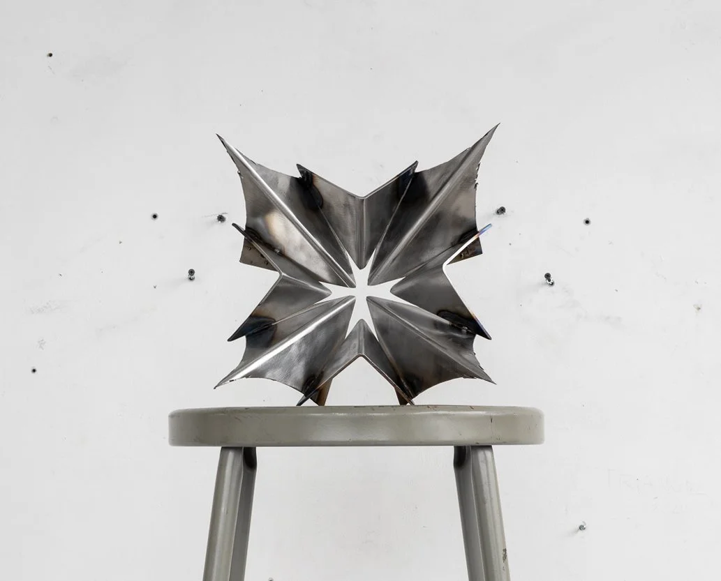Sculpture made of steel plates in a folded shape with jagged edges and a cross-shaped cutout in the center, tero Fuentes, Saint, 2025, steel, 9.5 x 6 in.