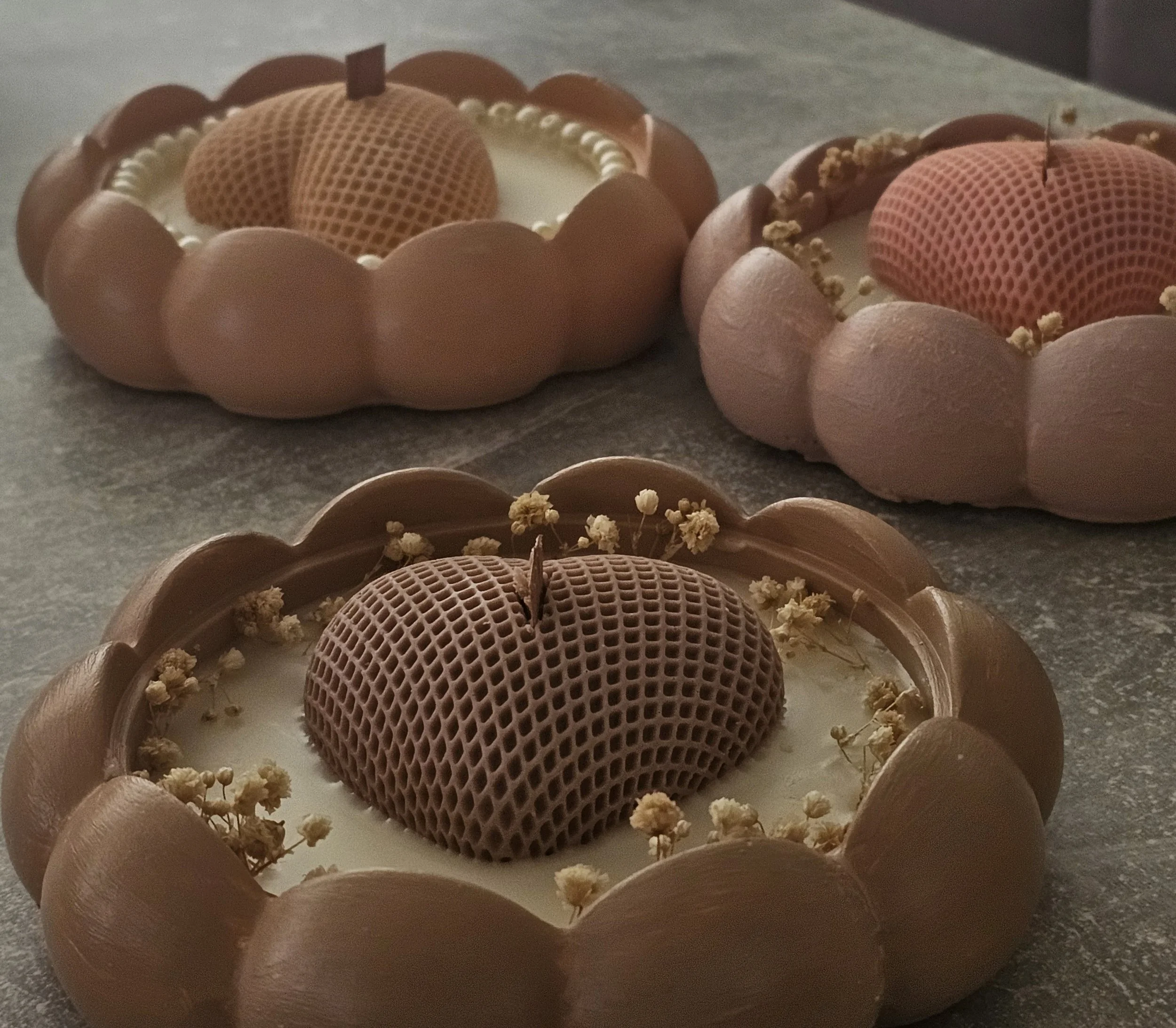 Schokoladenkuchen mit Dekoration aus Schokoladenkugeln, einem Milchring, einem Waffelherz und kleinen weißen Blüten.