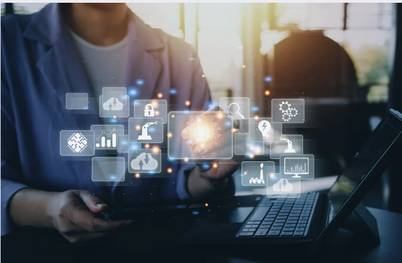 Person holding a futuristic holographic display of various technology and data icons in a modern office setting.