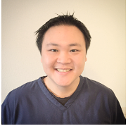A young person with short black hair and a big smile, wearing a navy blue shirt, posing against a plain light-colored background.