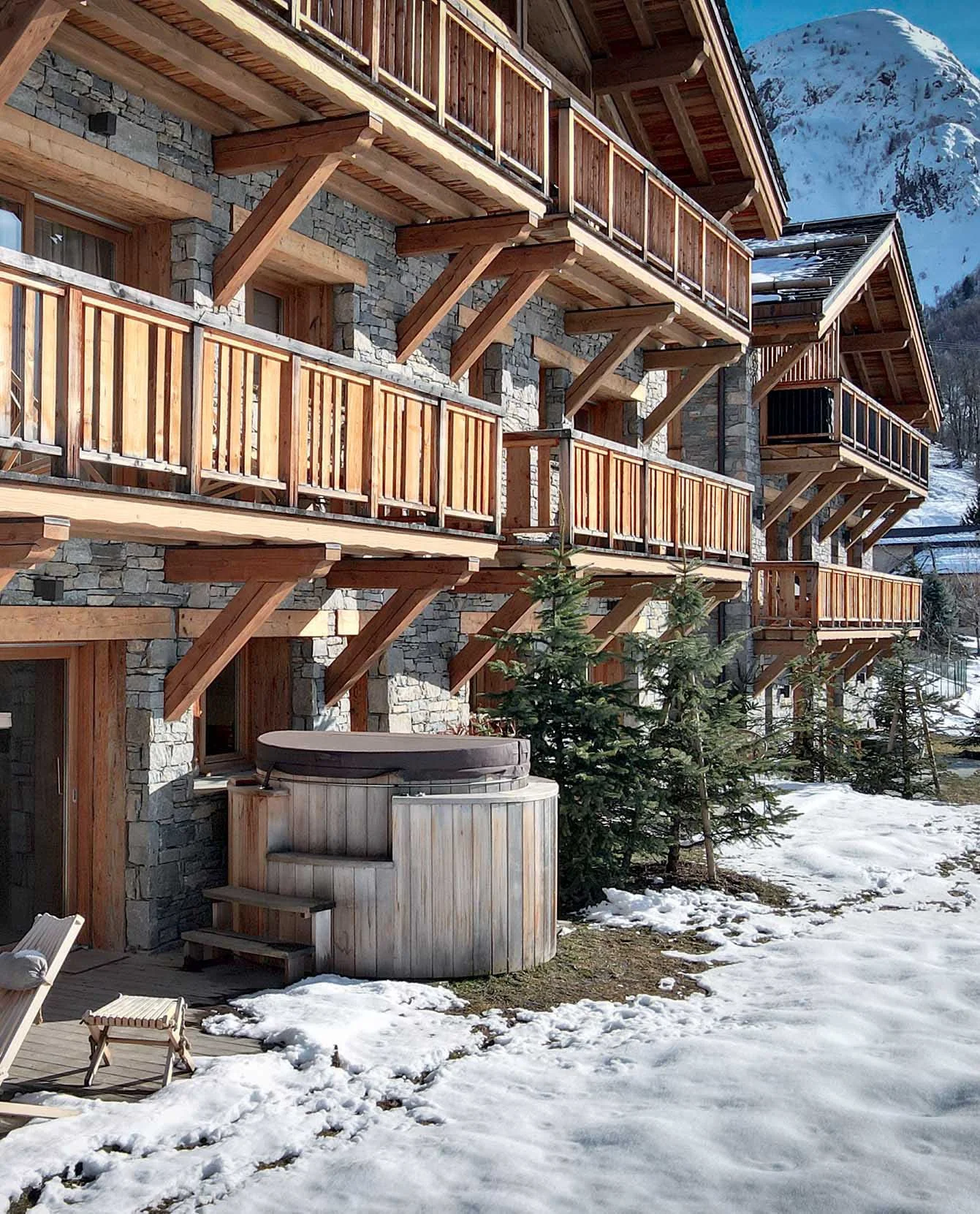 Ensemble résidentiel de style chalet proposé par HOME SUMMIT, avec façades en pierre et bois, terrasses privatives et environnement montagne d'exception.