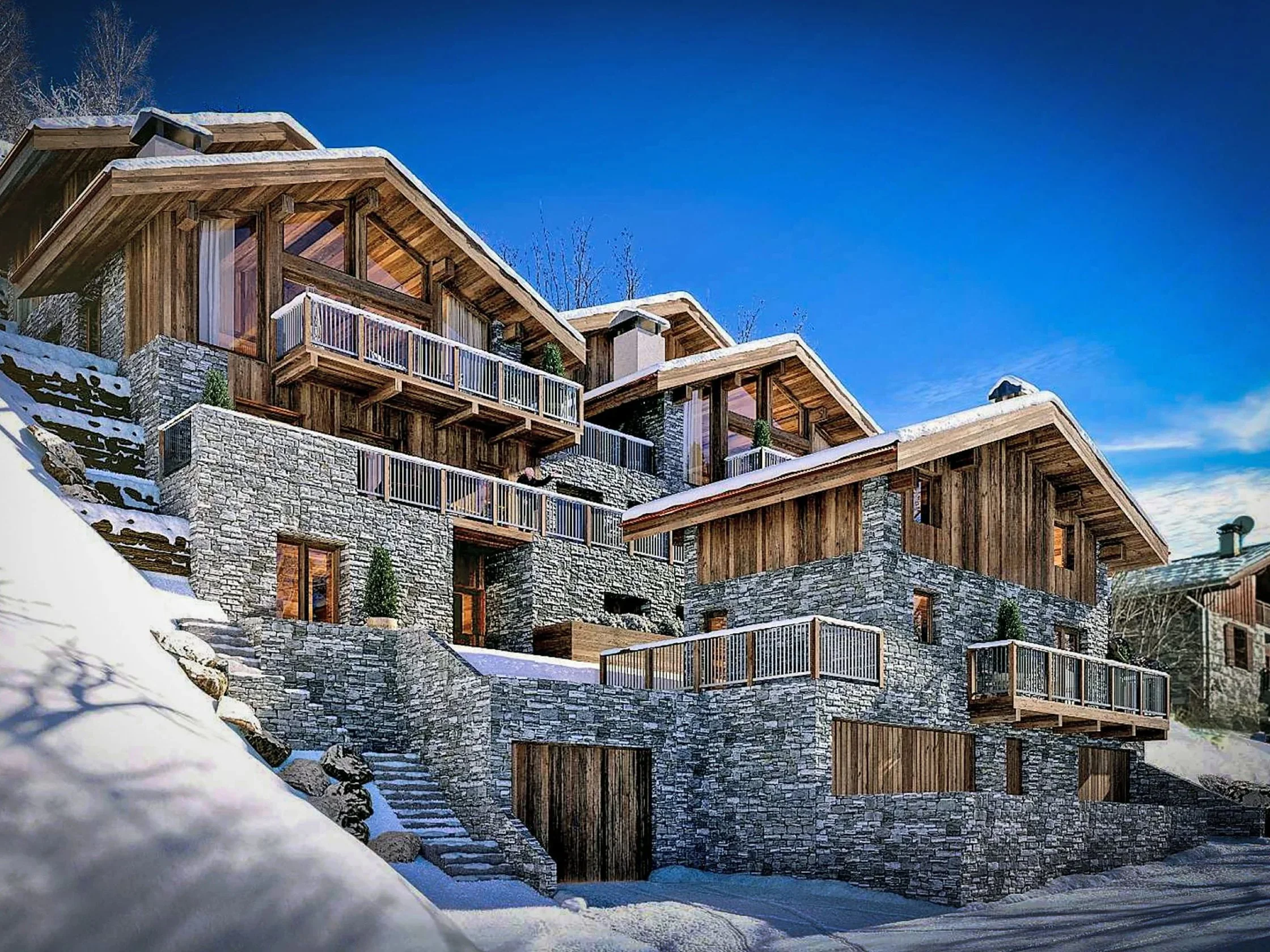 Vue hivernale d’un chalet de prestige en pierre et bois, avec grandes baies vitrées, balcons et terrasses, situé dans un village savoyard à proximité de Saint-Martin-de-Belleville, dans les 3 Vallées.