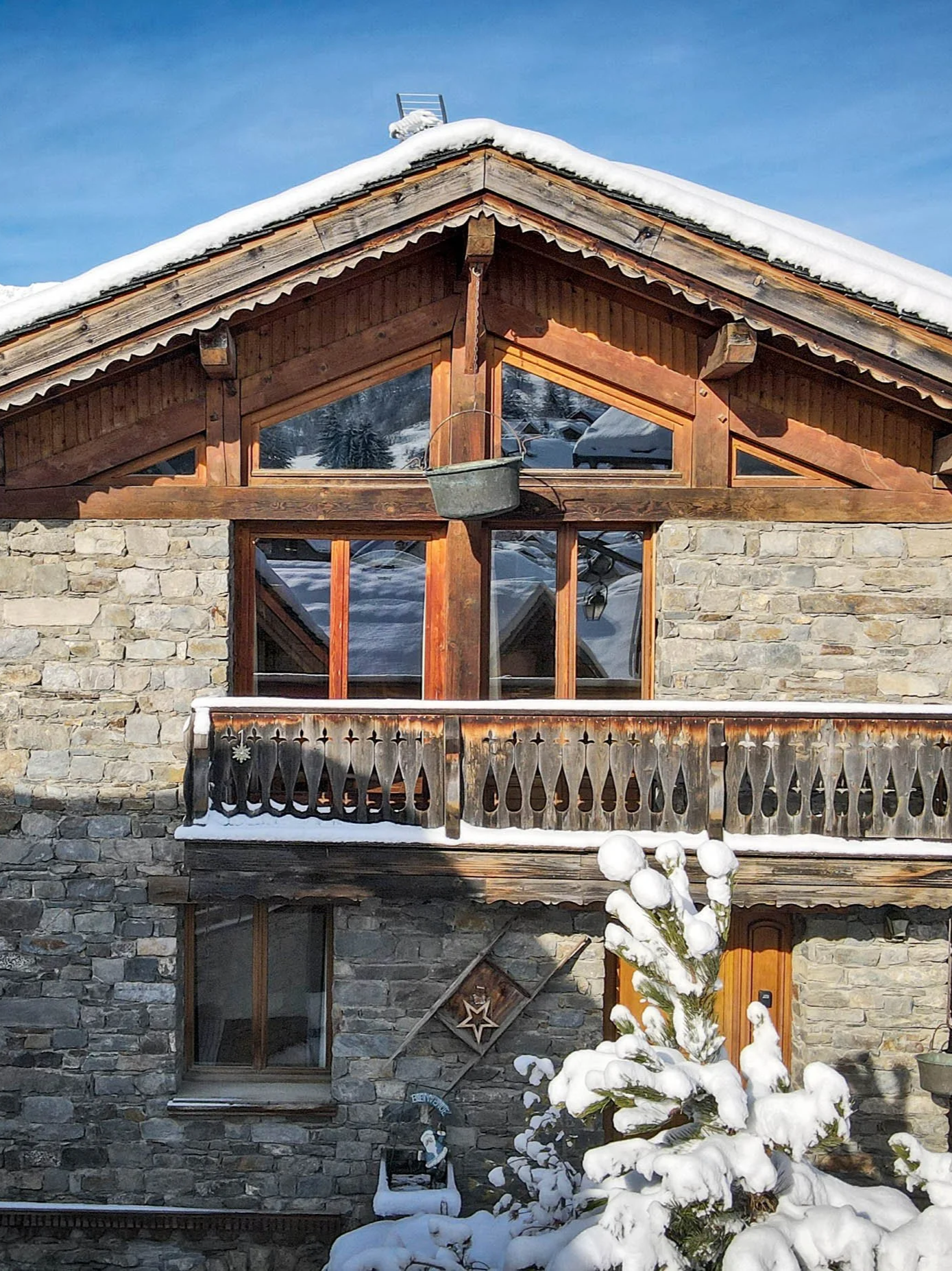 Chalet savoyard en pierre et bois proposé à la vente par HOME SUMMIT, bénéficiant d’un emplacement privilégié et d’une vue sur les sommets enneigés.