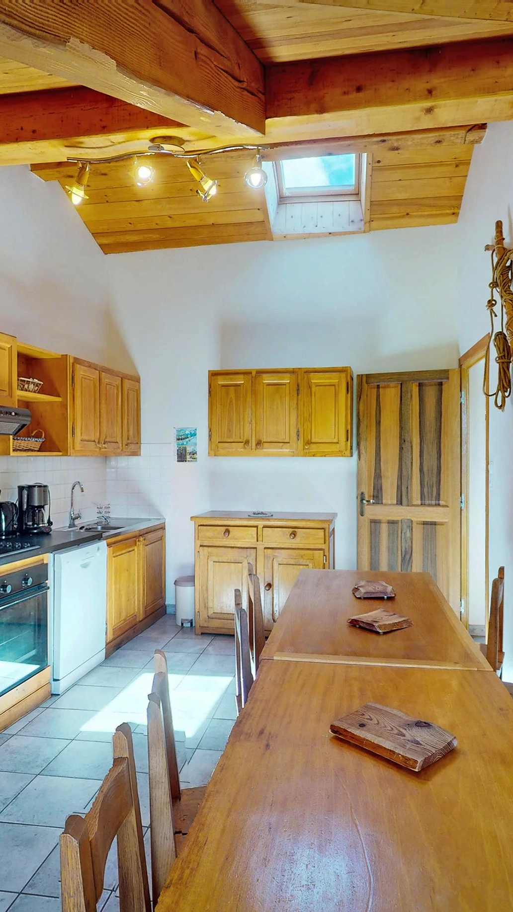 Cuisine équipée avec espace repas au sein d’un chalet proposé à la vente par HOME SUMMIT, alliant charme montagnard, poutres apparentes et ambiance chaleureuse.