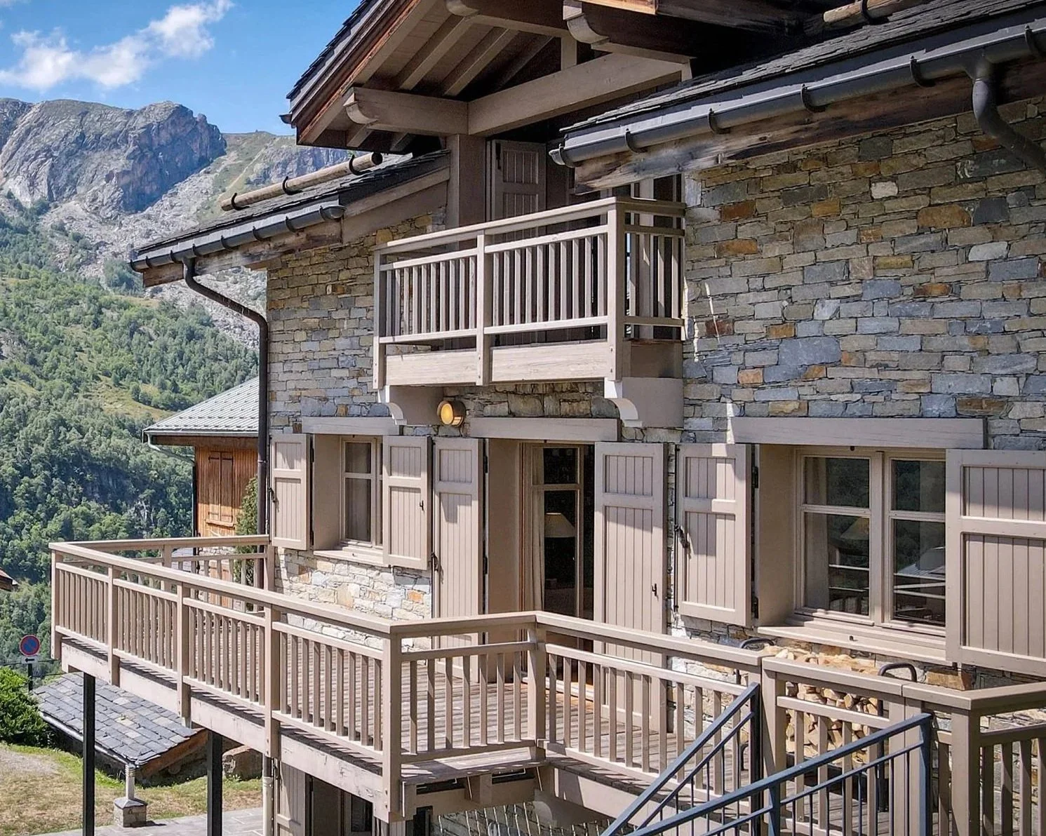Façade en pierre d’un chalet à vendre près de Saint-Martin-de-Belleville, avec grands balcons et vue dégagée sur les montagnes.